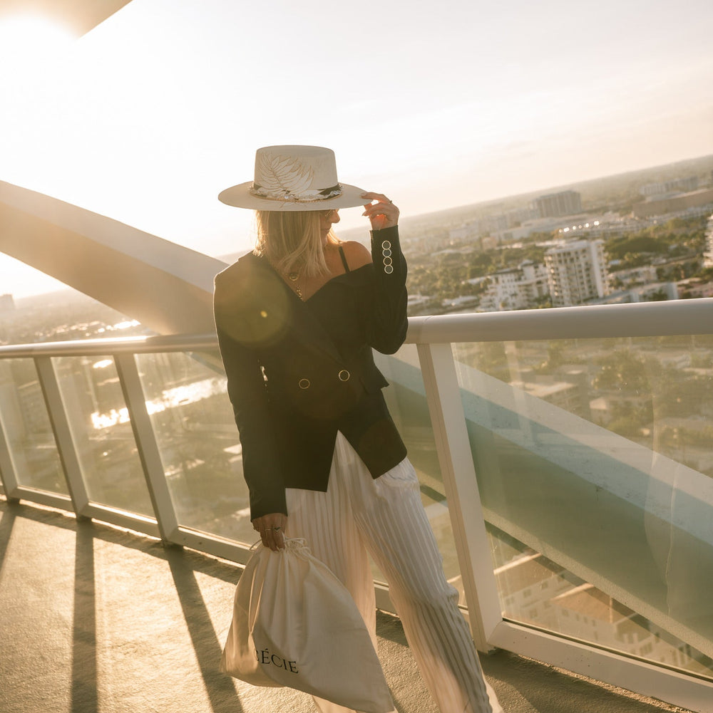Person standing on a balcony with a cityscape view during sunset.