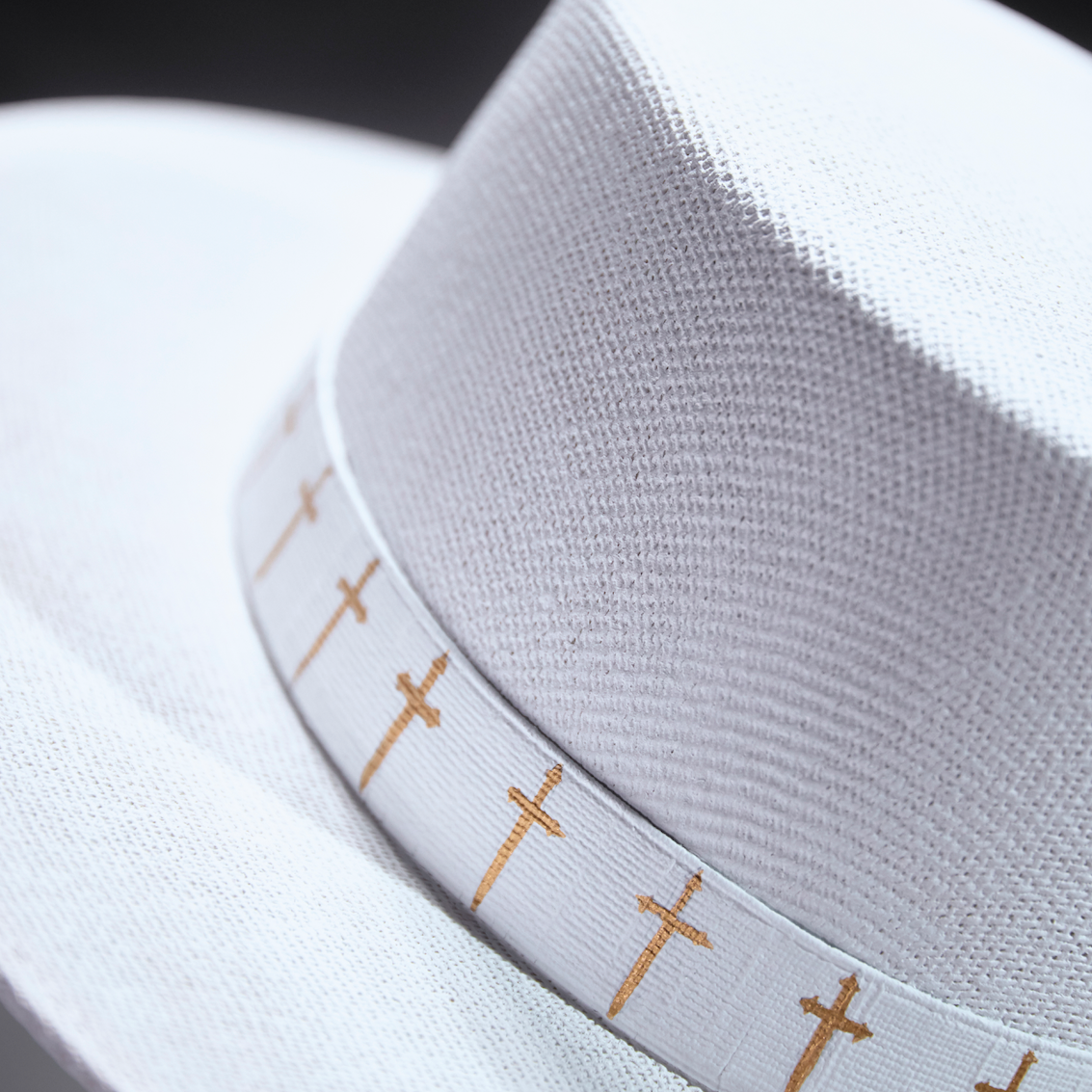 Close-up of a white hat with a decorative band featuring small crosses.