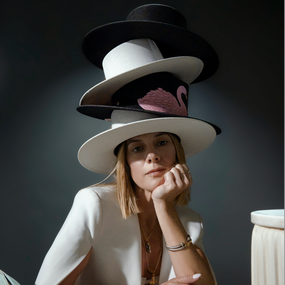 Person wearing multiple hats sitting at a table with a dark background