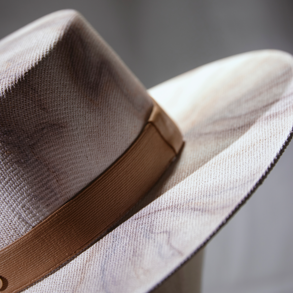 Close-up of a beige hat with a brown band on a blurred background